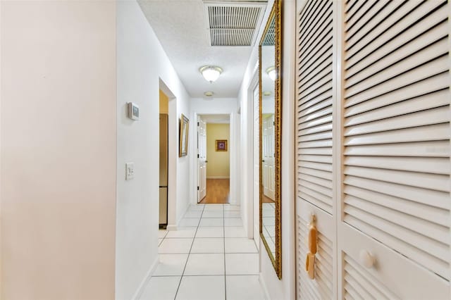 hallway featuring a textured ceiling and light tile patterned flooring