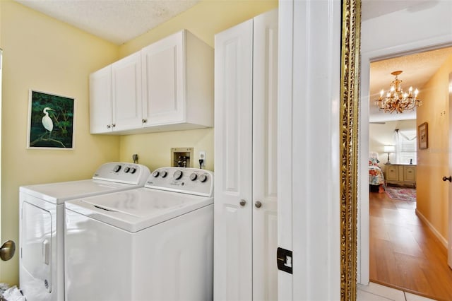 laundry area featuring a textured ceiling, washer and clothes dryer, cabinets, a chandelier, and light tile patterned flooring