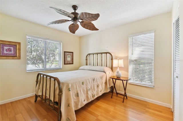 bedroom with ceiling fan, wood-type flooring, a closet, and a textured ceiling