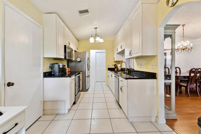 kitchen with white cabinetry, appliances with stainless steel finishes, a chandelier, and hanging light fixtures