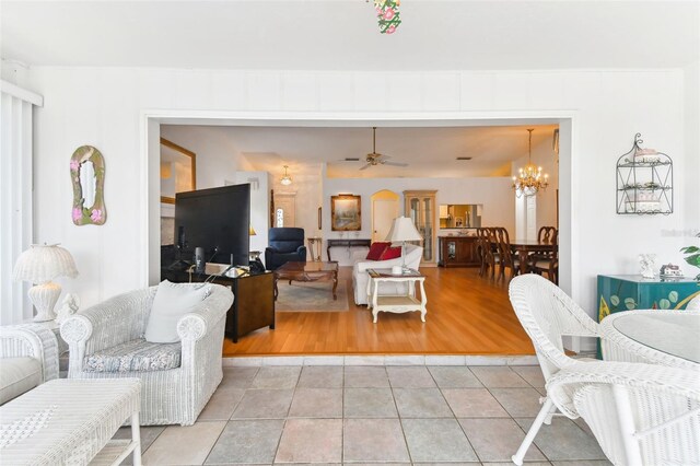 living room featuring ceiling fan with notable chandelier and light tile patterned floors