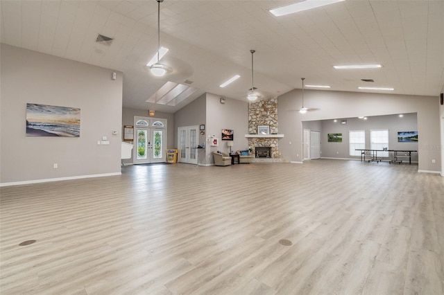 unfurnished living room with light hardwood / wood-style floors, a high ceiling, a healthy amount of sunlight, and a fireplace