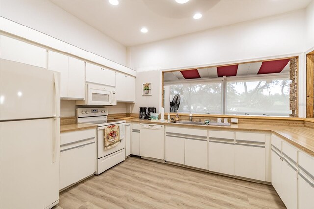 kitchen featuring sink, light hardwood / wood-style floors, white cabinets, and white appliances