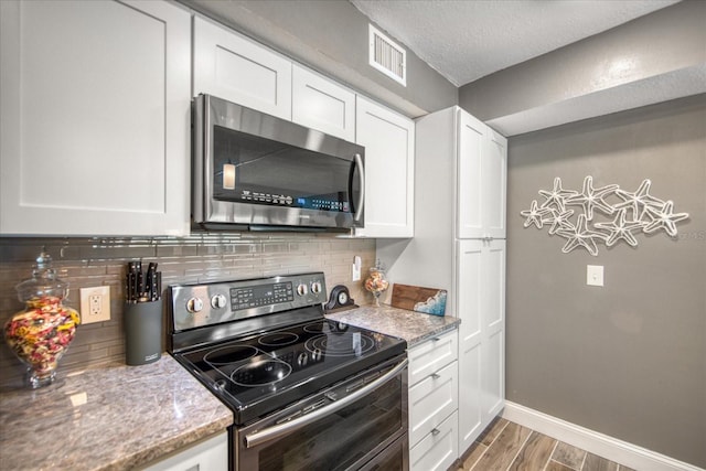 kitchen featuring tasteful backsplash, appliances with stainless steel finishes, and white cabinets