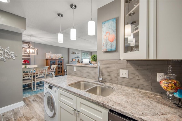 kitchen featuring hanging light fixtures, sink, washer / dryer, and light wood-type flooring