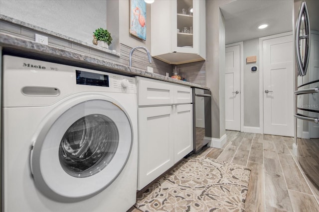 clothes washing area featuring light hardwood / wood-style floors and washer / clothes dryer