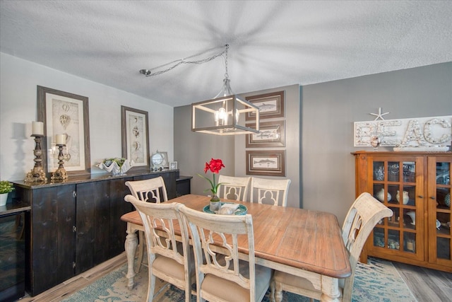 dining area with an inviting chandelier, light hardwood / wood-style flooring, and a textured ceiling