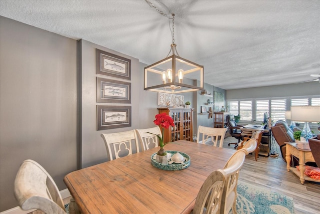 dining space with wood-type flooring, a textured ceiling, and a chandelier