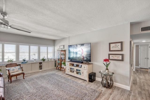 living room with ceiling fan, hardwood / wood-style flooring, and a textured ceiling