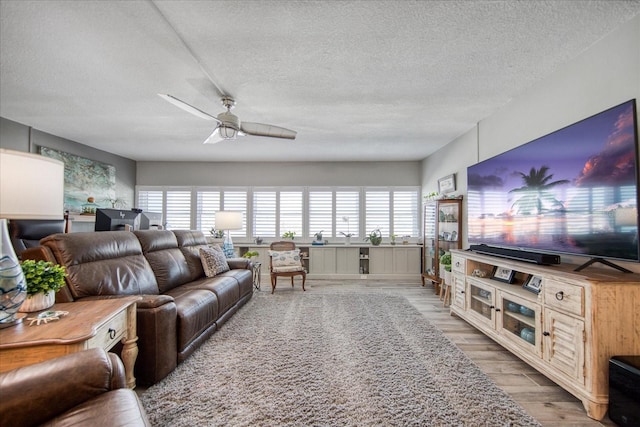 living room with hardwood / wood-style floors, ceiling fan, and a textured ceiling