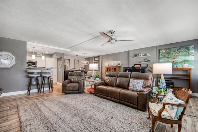 living room with wood-type flooring, ceiling fan, and a textured ceiling