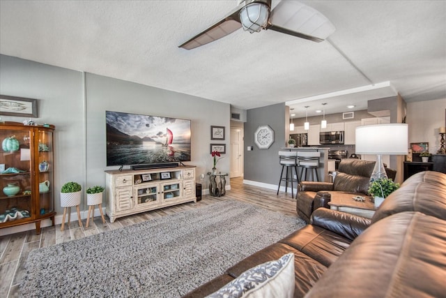 living room with wood-type flooring, a textured ceiling, and ceiling fan