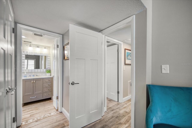 bedroom with ensuite bath, light hardwood / wood-style flooring, and sink