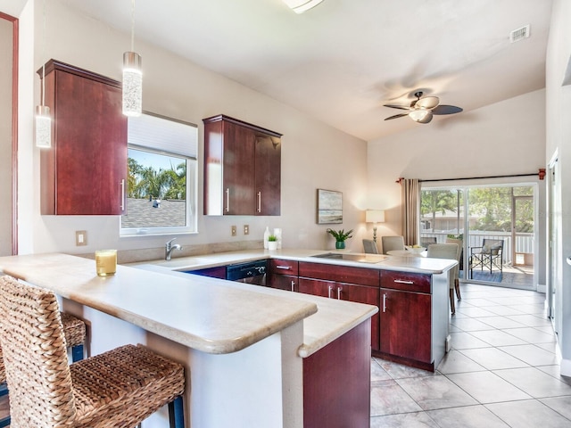 kitchen featuring kitchen peninsula, a kitchen bar, pendant lighting, dishwasher, and light tile patterned flooring