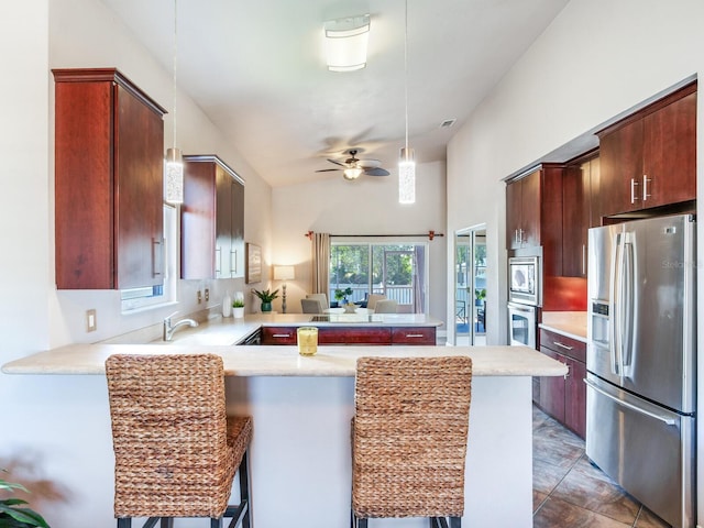 kitchen with ceiling fan, hanging light fixtures, kitchen peninsula, a breakfast bar area, and appliances with stainless steel finishes