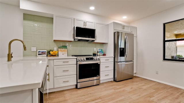 kitchen featuring sink, light hardwood / wood-style flooring, backsplash, and stainless steel appliances