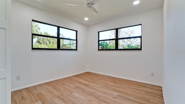 empty room featuring a wealth of natural light, light hardwood / wood-style floors, and ceiling fan