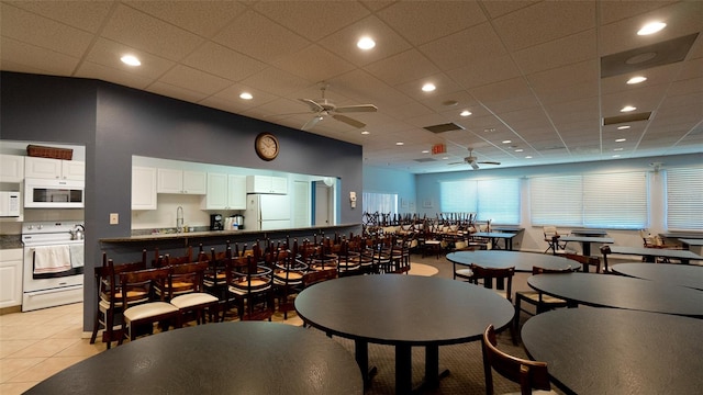 tiled dining area featuring sink, ceiling fan, and a paneled ceiling