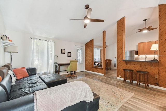 living room with a healthy amount of sunlight, ceiling fan, vaulted ceiling, and light wood-type flooring