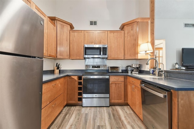 kitchen featuring kitchen peninsula, stainless steel appliances, sink, and light wood-type flooring