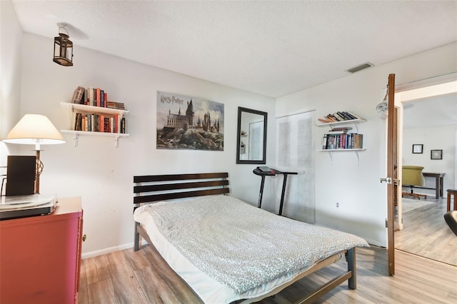 bedroom with wood-type flooring, a textured ceiling, and a closet