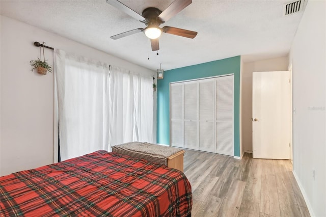 bedroom with light hardwood / wood-style flooring, ceiling fan, a closet, and a textured ceiling