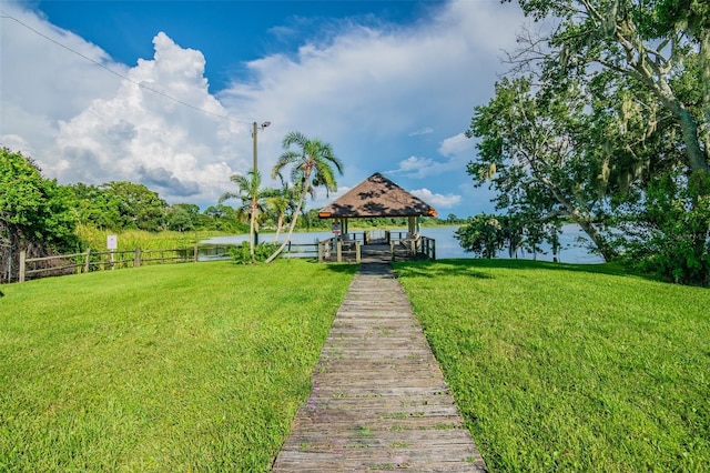 view of dock with a yard, a water view, and a gazebo