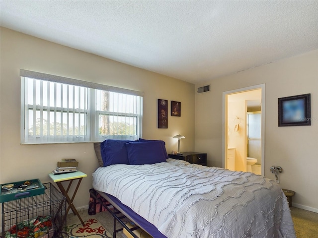 carpeted bedroom featuring a textured ceiling and ensuite bathroom