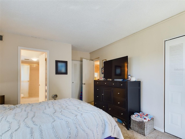 bedroom featuring light colored carpet, a textured ceiling, two closets, and ensuite bathroom