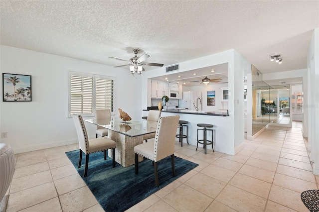 dining space with ceiling fan, a textured ceiling, light tile patterned floors, and sink