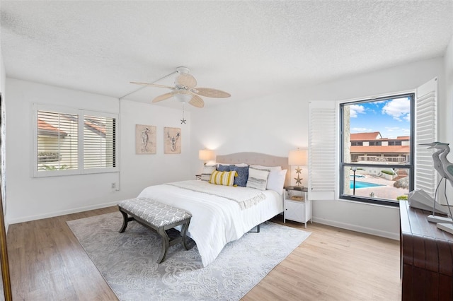 bedroom with ceiling fan, a textured ceiling, light wood-type flooring, and multiple windows