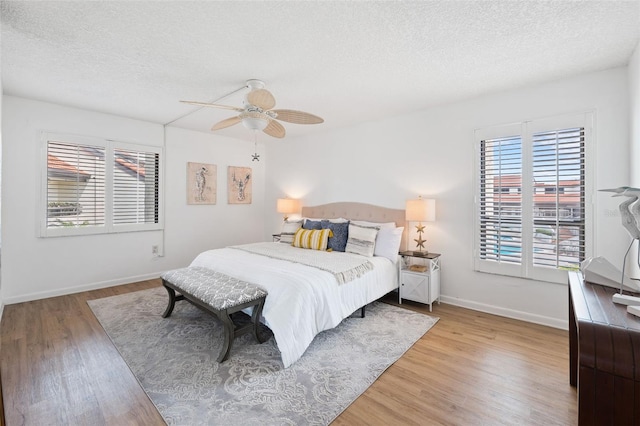 bedroom featuring ceiling fan, a textured ceiling, and light hardwood / wood-style flooring