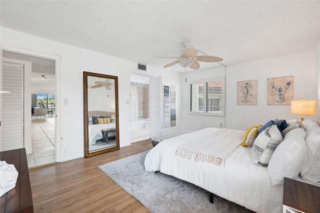 bedroom featuring ceiling fan, connected bathroom, hardwood / wood-style floors, and multiple windows