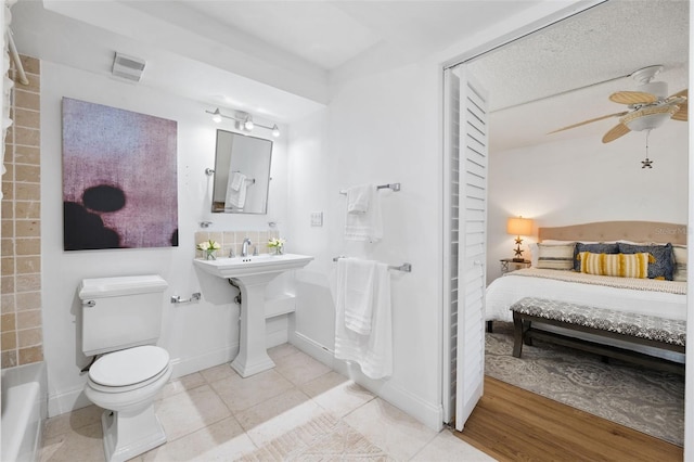 bathroom with a textured ceiling, wood-type flooring, toilet, and ceiling fan