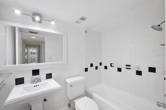 full bathroom with decorative backsplash, sink, tiled shower / bath, and toilet