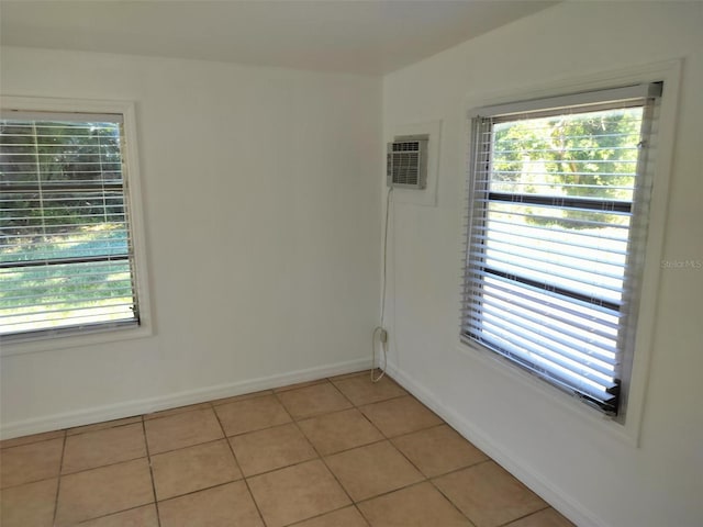 empty room featuring light tile patterned floors, an AC wall unit, and plenty of natural light