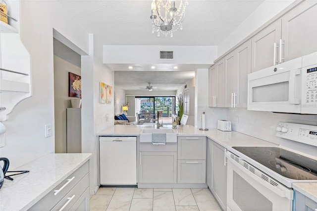 kitchen with sink, white appliances, ceiling fan with notable chandelier, and a textured ceiling