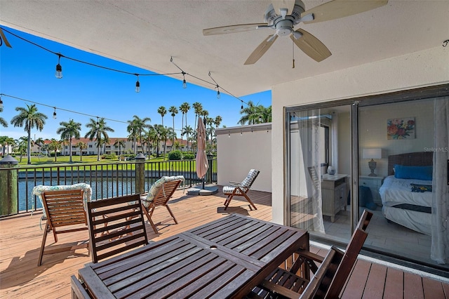 wooden deck with a water view and ceiling fan