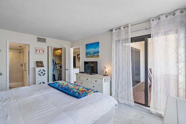 tiled bedroom with a textured ceiling, a closet, and a walk in closet