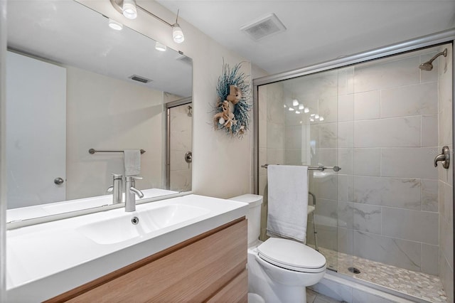 bathroom featuring tile floors, vanity, toilet, and a shower with shower door