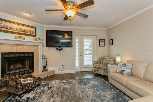 living room featuring crown molding, wood-type flooring, ceiling fan, and a tile fireplace