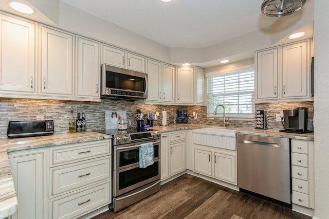 kitchen with stainless steel appliances, tasteful backsplash, dark wood-type flooring, light stone counters, and sink