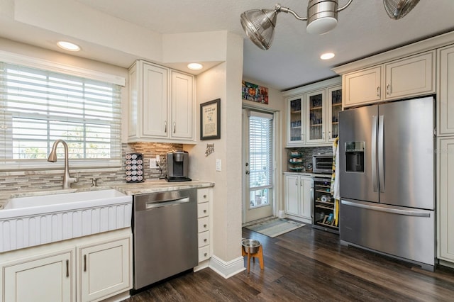 kitchen with light stone counters, sink, tasteful backsplash, stainless steel appliances, and dark hardwood / wood-style floors