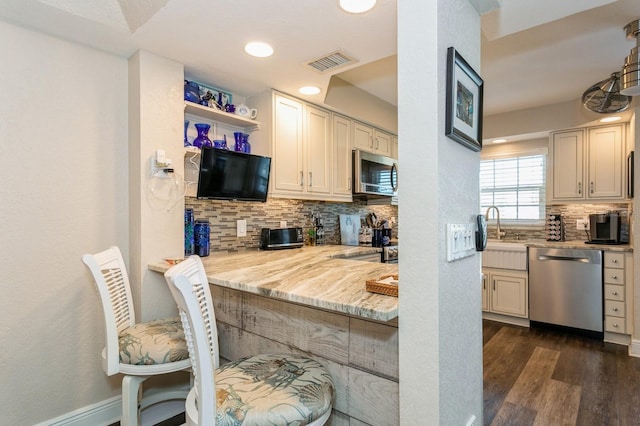 kitchen with tasteful backsplash, stainless steel appliances, light stone countertops, and dark hardwood / wood-style flooring