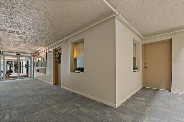 corridor with a textured ceiling and dark carpet