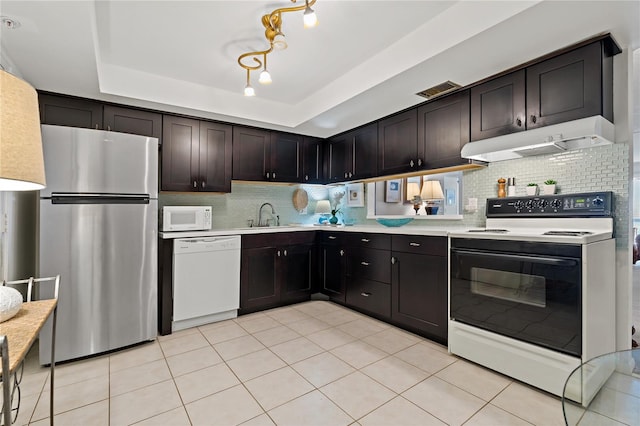 kitchen with light tile floors, white appliances, a raised ceiling, and tasteful backsplash