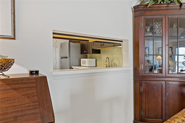 interior details with sink, backsplash, and stainless steel refrigerator