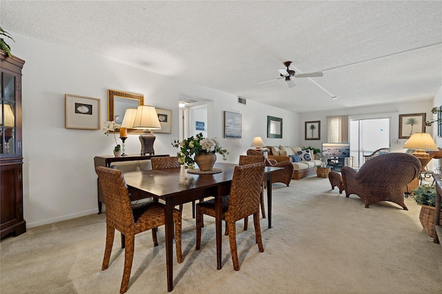 dining room with light carpet, ceiling fan, and a textured ceiling