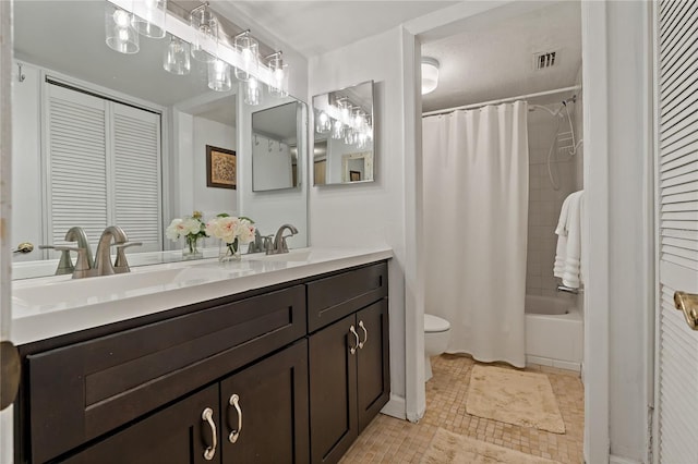 full bathroom with dual vanity, toilet, tile floors, and shower / tub combo