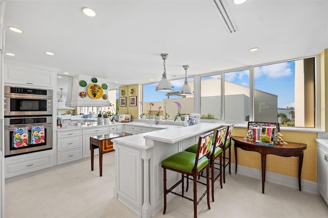 kitchen with light tile flooring, kitchen peninsula, a breakfast bar area, stainless steel double oven, and pendant lighting